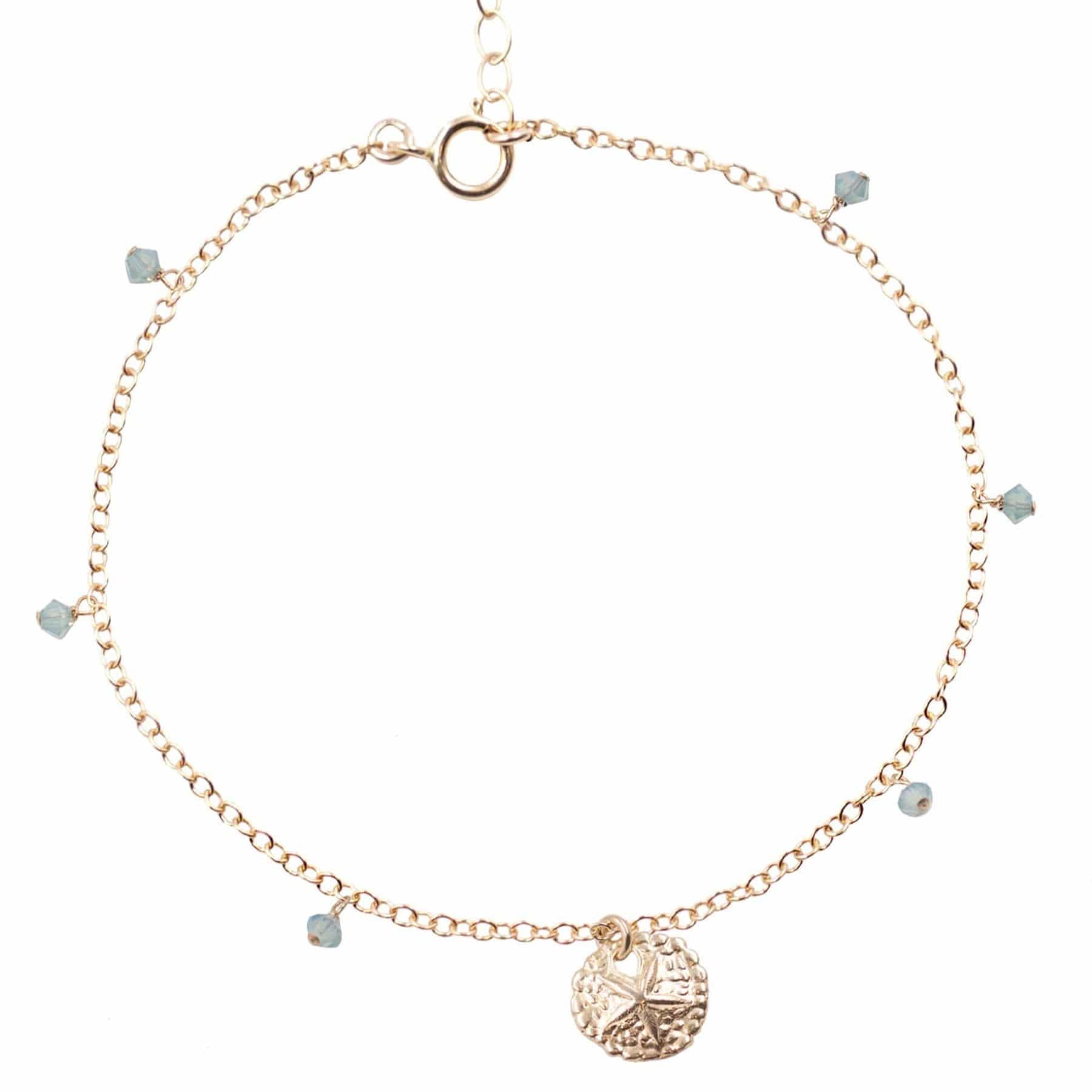 close up of dainty gold sand dollar anklet on white background