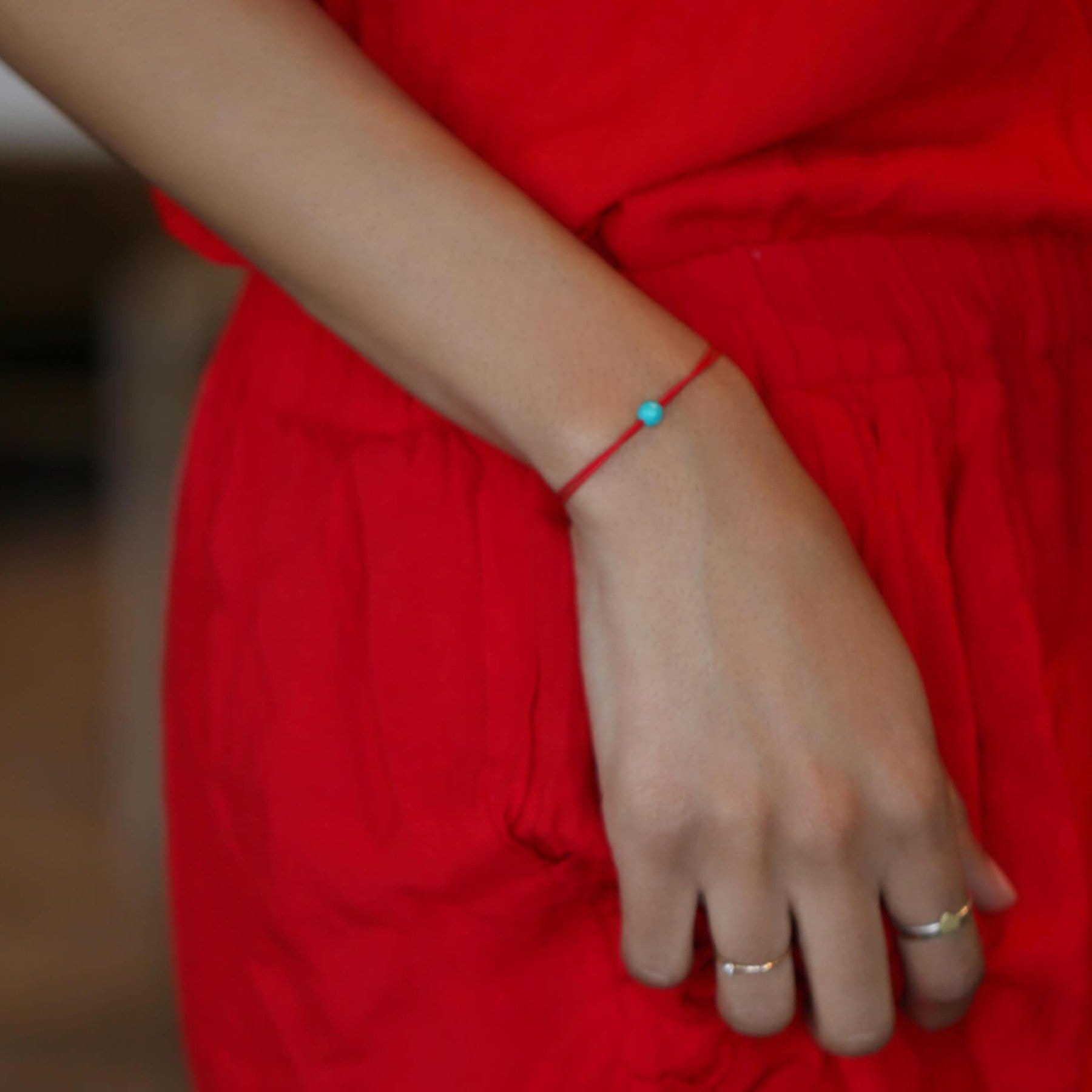Happy Thoughts bracelet turquoise stone in contrast with red.