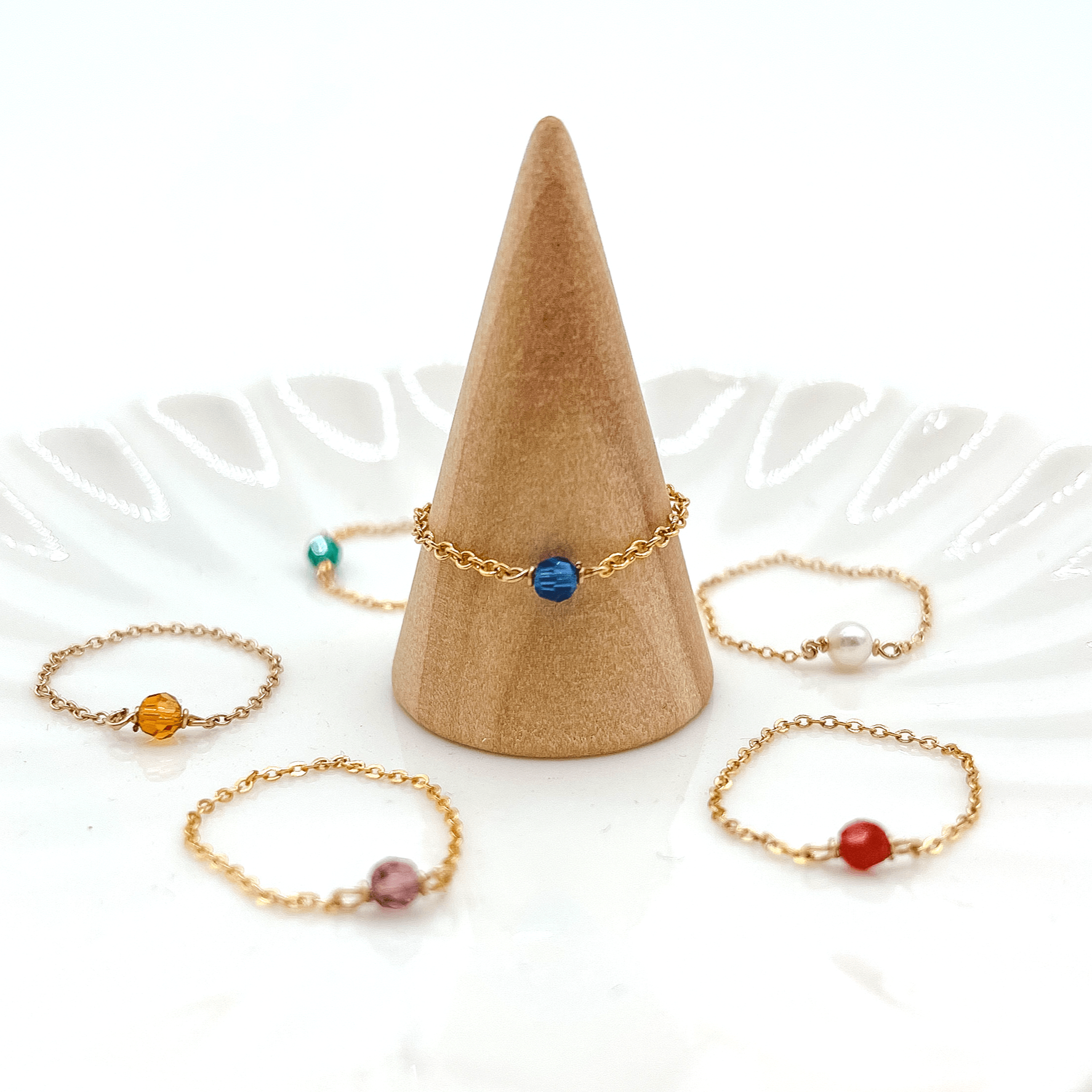 variety of birthstone rings on ring holder and plate