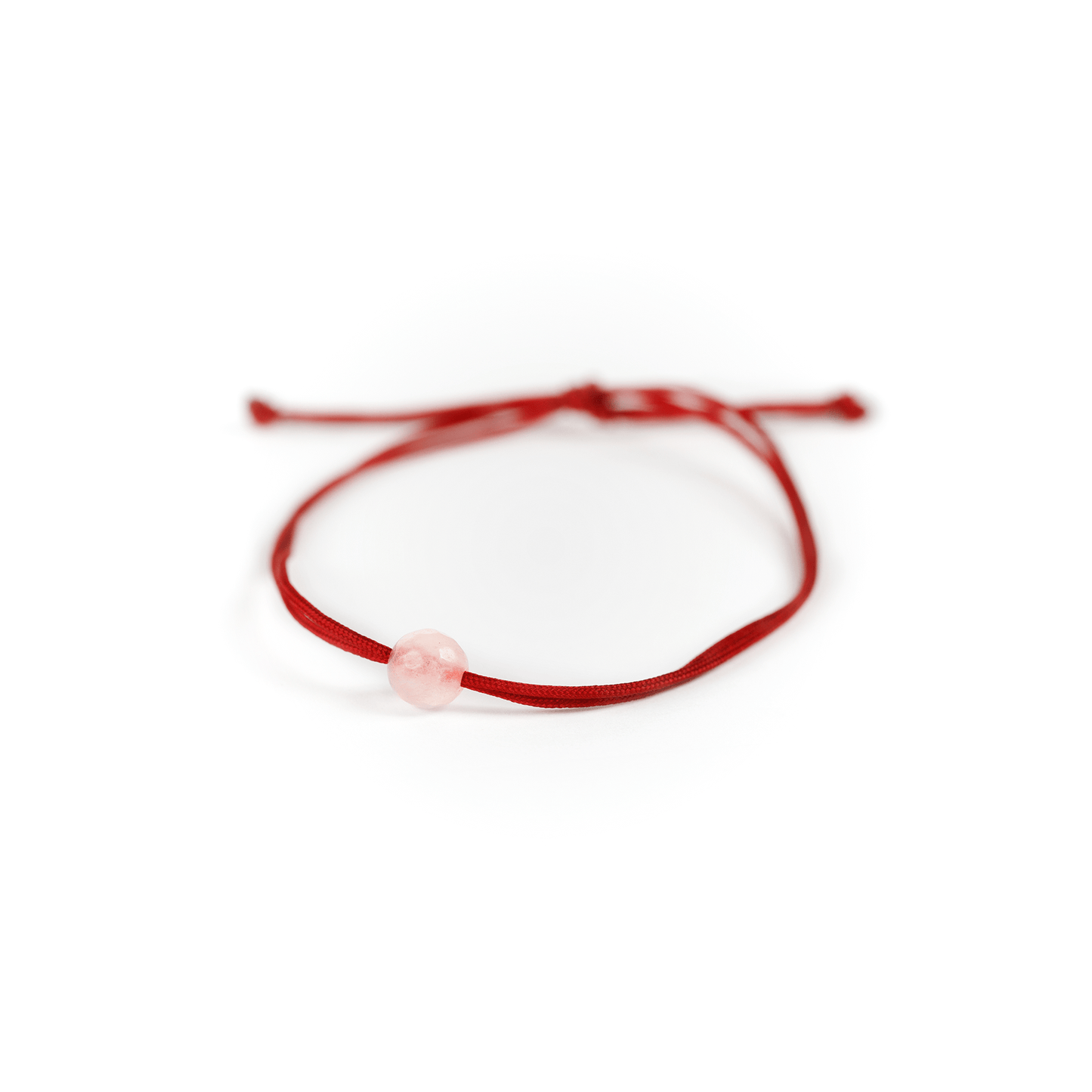 Close up of the rose quartz stone on red nylon string.