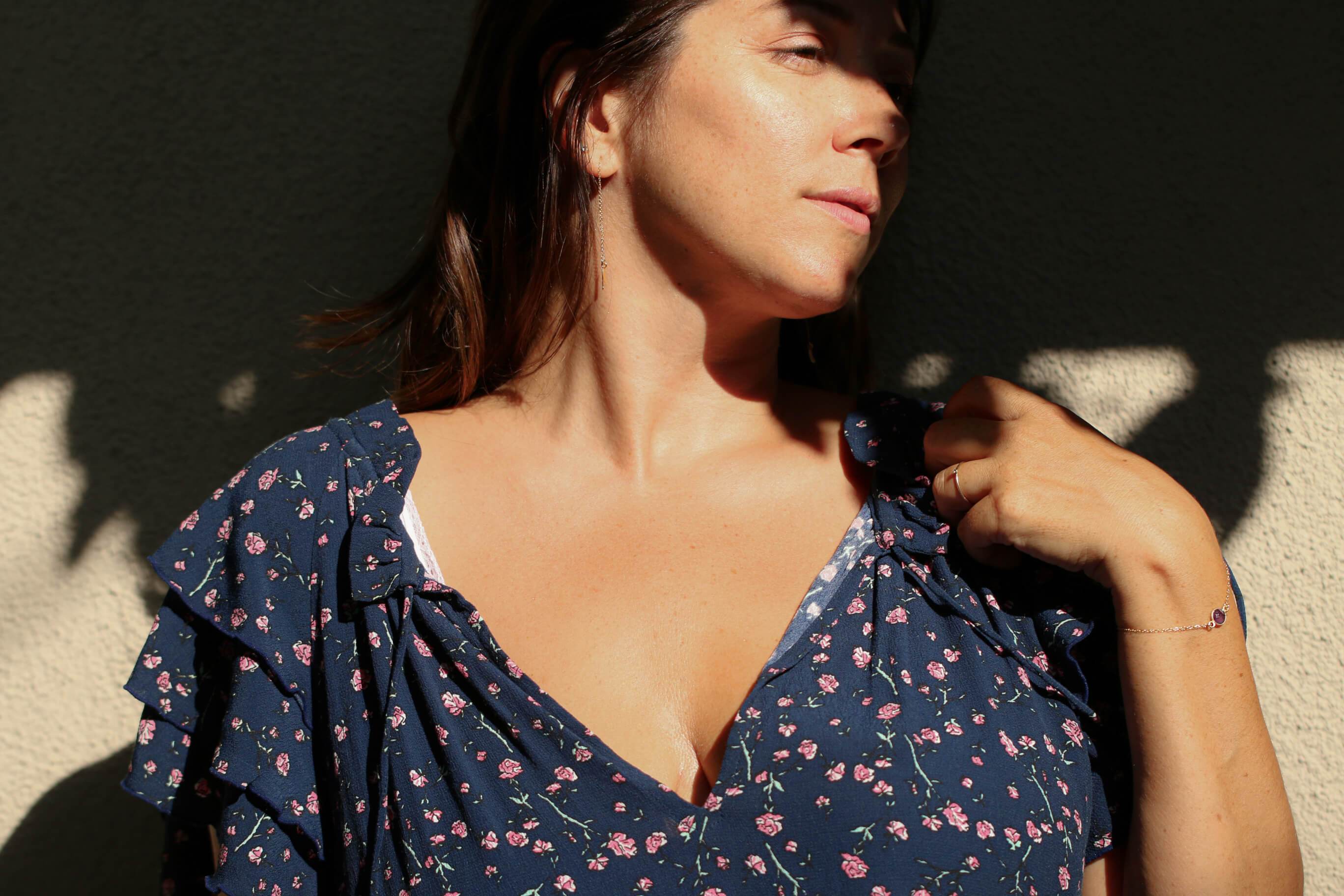 Model in dappled light wearing a floral shirt and an genuine amethyst stone bracelet in gold - MaeMae Jewelry