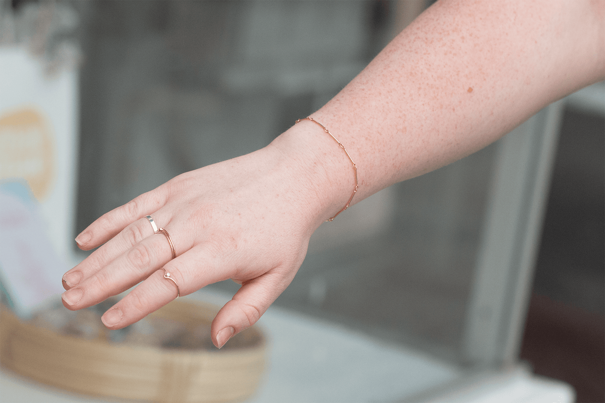Be Kind gold filled bracelet modeled on hand with rings