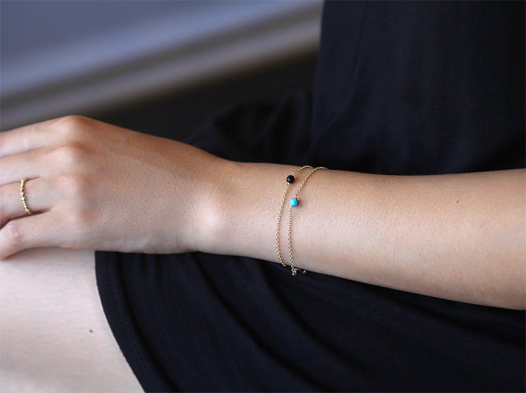  Lifestyle Photo Model Wearing Dainty Stone Bracelets in Gold - MaeMae Jewelry - Stack of Two - Turquoise and Black Onyx