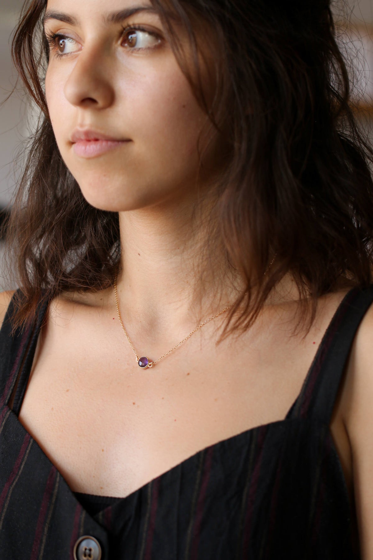 Short, wavy, brown haired model wearing a genuine amethyst gold necklace - MaeMae Jewelry