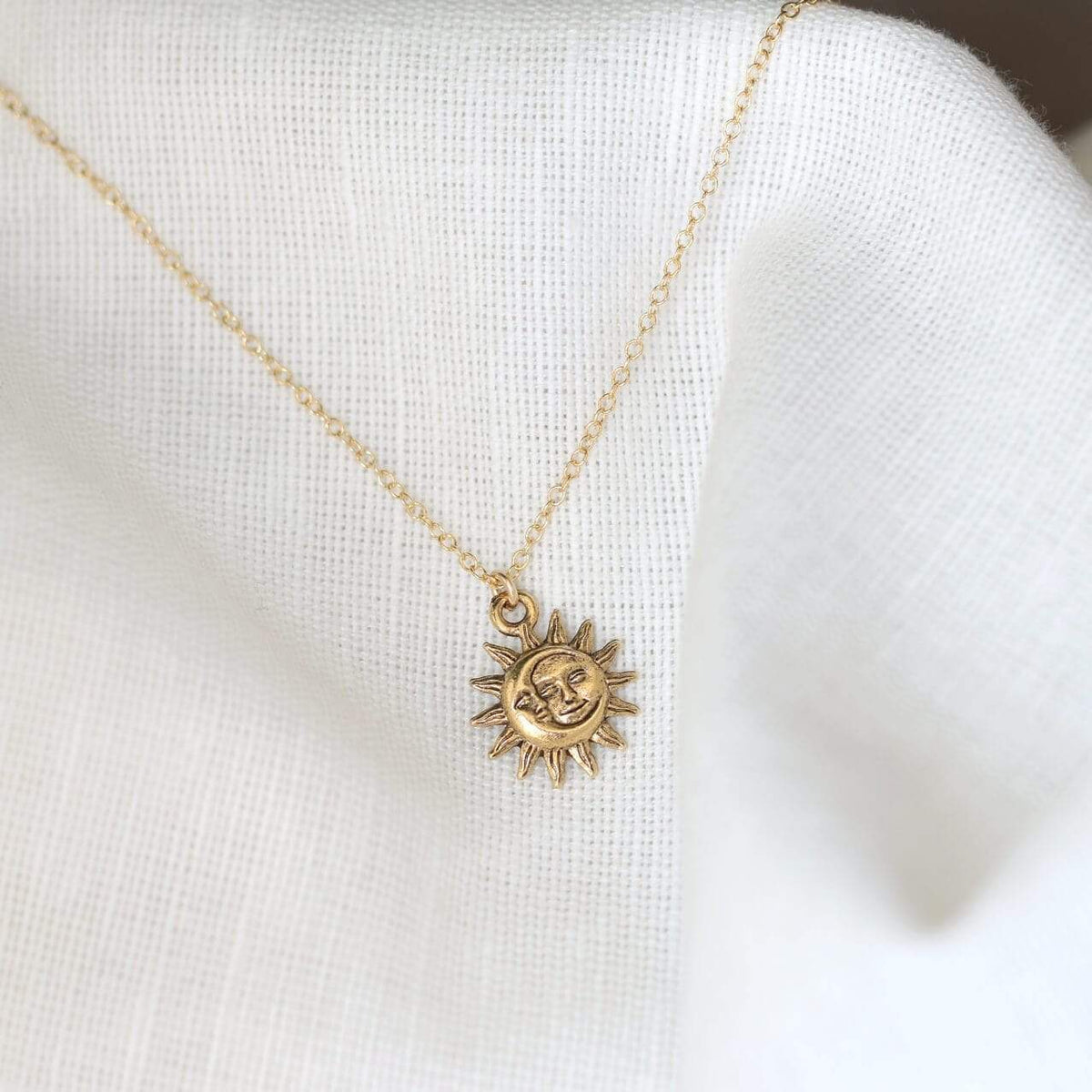 Detail view of 14K Gold Filled Light After Dark Necklace with Gold Sun Moon Charm on white background.